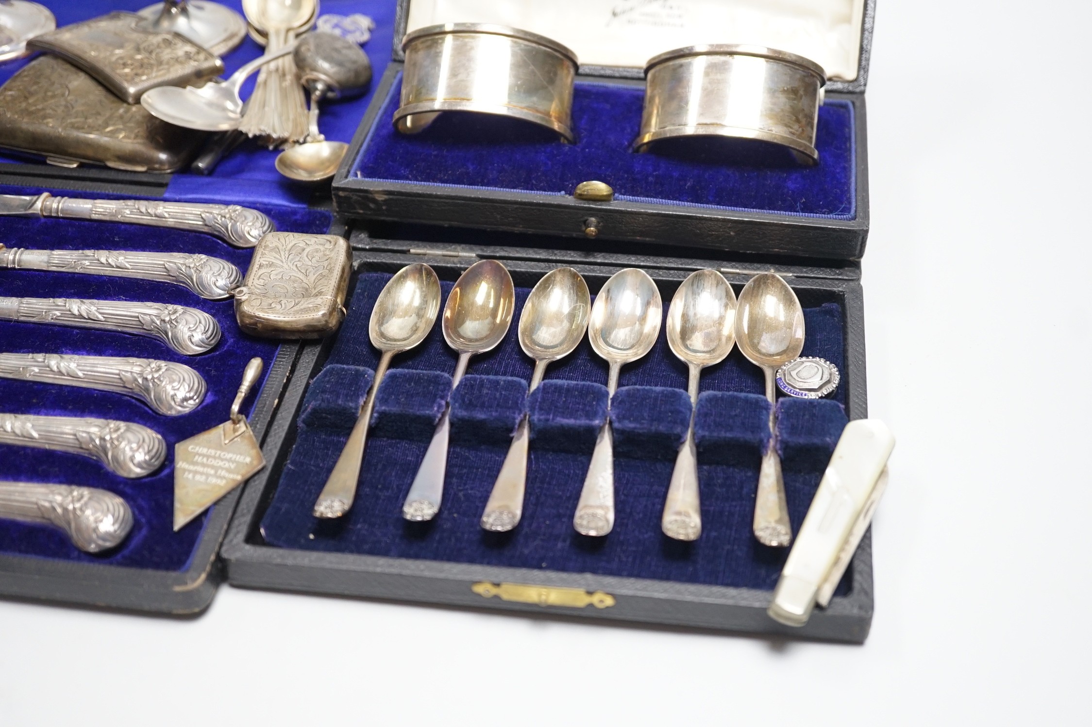 A mixed group of assorted silver ware including a pair of vases, 13.1cm, weighted, cased and loose napkin rings, cased teaspoons, cased silver pistol handled tea knives, sovereign case, mother of pearl handled fruit knif